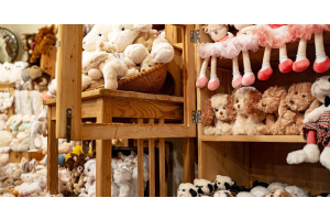 Multiple wooden shelves of plush toys with different designs. Some toys are sheep, dogs, and penguins.