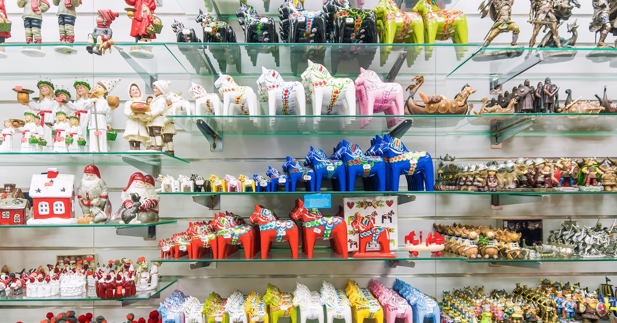 Glass shelves hanging on a wall filled with colorful knickknacks. There are small figurines of horses, people, and houses.